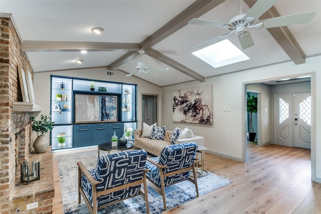 living room with ceiling fan, light hardwood / wood-style flooring, and vaulted ceiling with skylight