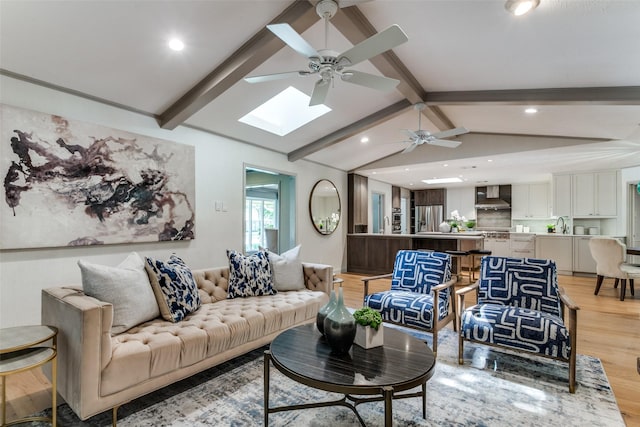 living room with lofted ceiling with skylight, ceiling fan, and light hardwood / wood-style floors