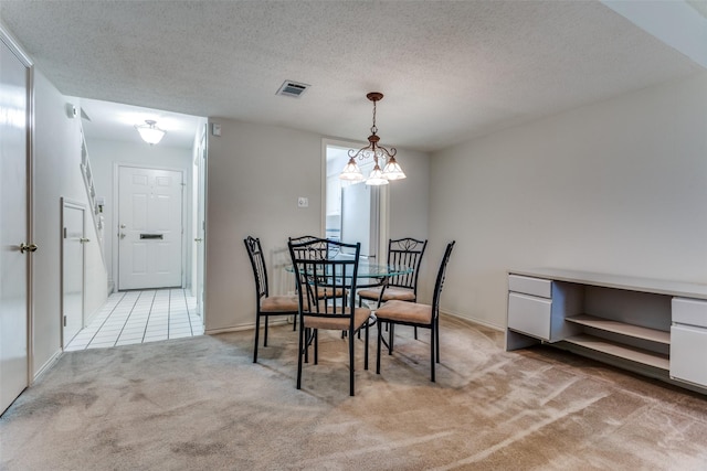 dining room featuring a textured ceiling, light colored carpet, and a chandelier