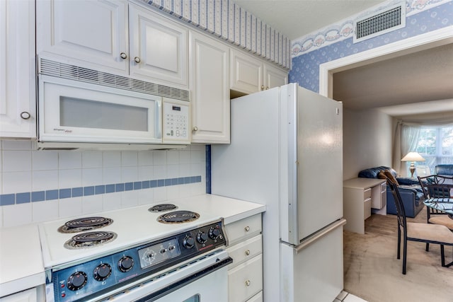 kitchen with tasteful backsplash, white appliances, and white cabinets