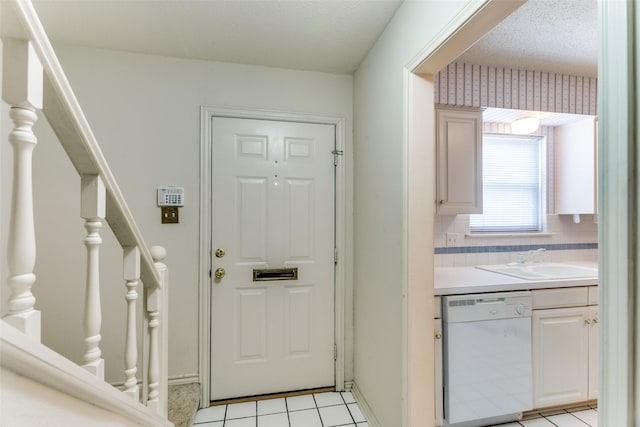 tiled entrance foyer with sink and a textured ceiling