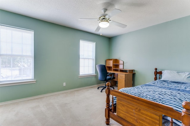 bedroom with ceiling fan, light colored carpet, and a textured ceiling