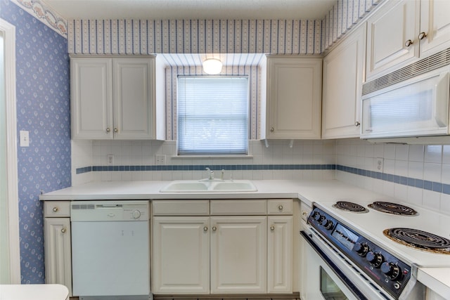 kitchen with tasteful backsplash, sink, white cabinets, and white appliances