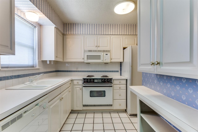 kitchen featuring sink, white appliances, light tile patterned floors, white cabinetry, and a textured ceiling