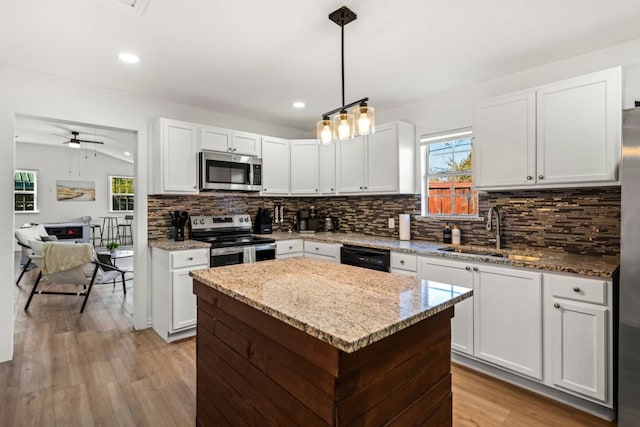 kitchen featuring a center island, stainless steel appliances, lofted ceiling, a sink, and light wood-type flooring