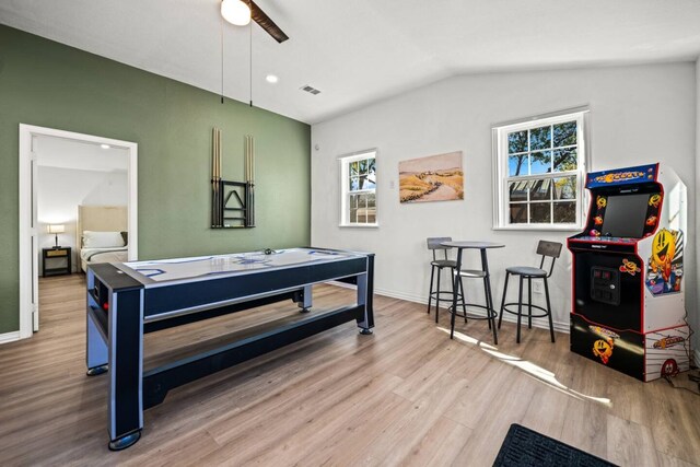 living room with ceiling fan, light hardwood / wood-style floors, and vaulted ceiling