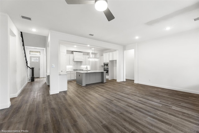 kitchen with premium range hood, open floor plan, an island with sink, appliances with stainless steel finishes, and white cabinetry