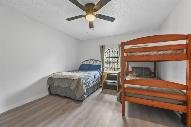 bedroom with wood-type flooring, a textured ceiling, and ceiling fan