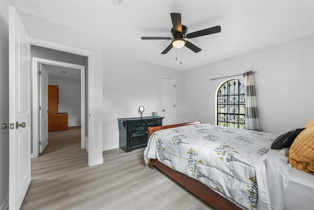 bedroom featuring light wood-type flooring, a textured ceiling, and ceiling fan