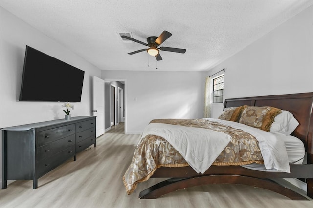 bedroom with a textured ceiling, ceiling fan, and light wood-type flooring