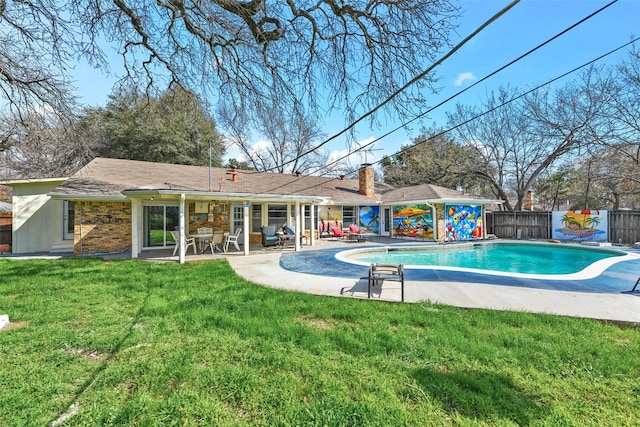 rear view of house with a fenced in pool, a lawn, and a patio area