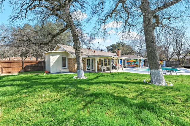 back of house featuring a yard, a fenced in pool, and a patio area