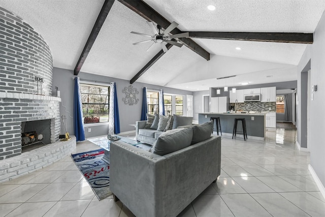 living room featuring a brick fireplace, vaulted ceiling with beams, sink, and a textured ceiling