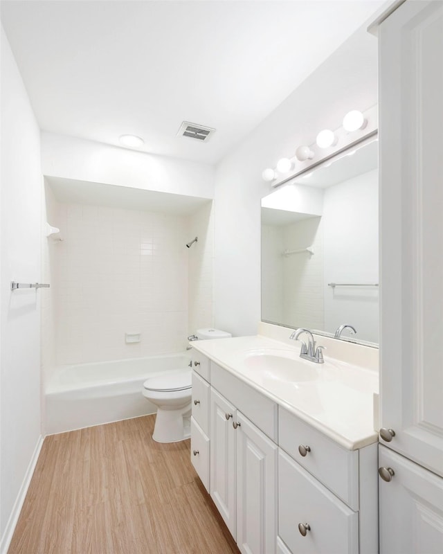 full bathroom with hardwood / wood-style flooring, tiled shower / bath, vanity, and toilet