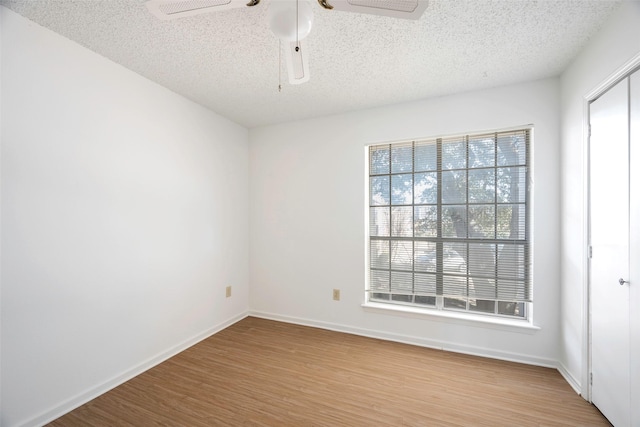 spare room with ceiling fan, plenty of natural light, light hardwood / wood-style floors, and a textured ceiling