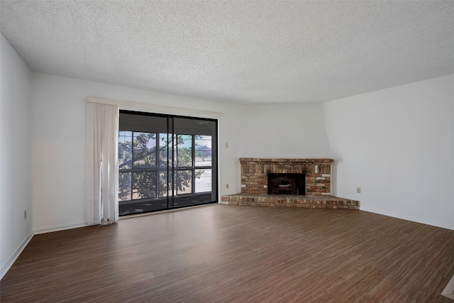 unfurnished living room featuring dark hardwood / wood-style flooring, a brick fireplace, and a textured ceiling