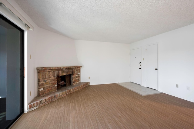 unfurnished living room with a fireplace, light hardwood / wood-style floors, and a textured ceiling