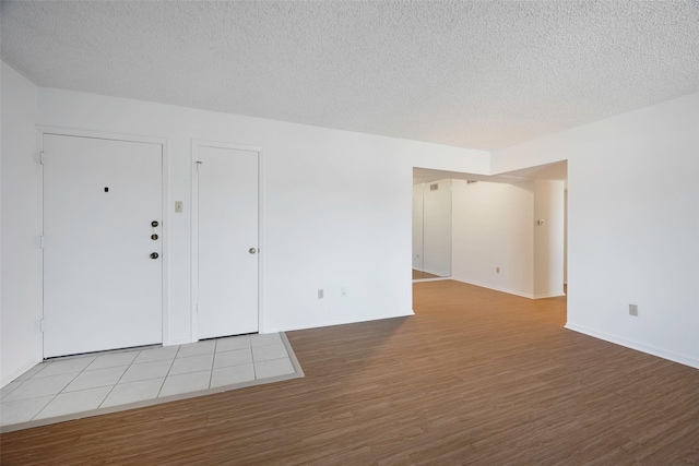 empty room with light hardwood / wood-style flooring and a textured ceiling