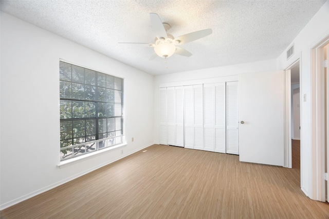 unfurnished bedroom with a textured ceiling, light hardwood / wood-style floors, a closet, and ceiling fan