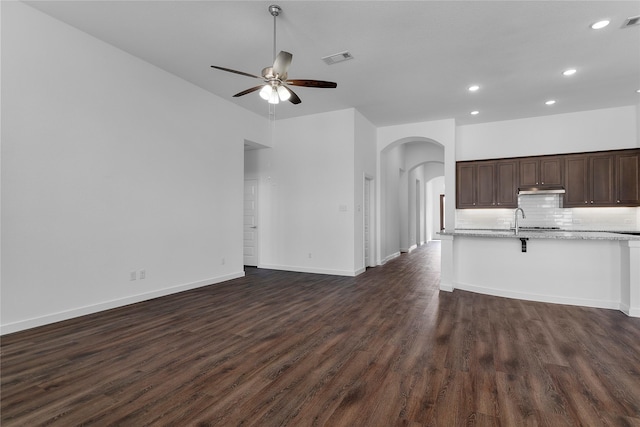 unfurnished living room with dark wood-type flooring, ceiling fan, and sink