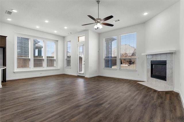 unfurnished living room with a tile fireplace, plenty of natural light, dark hardwood / wood-style floors, and ceiling fan