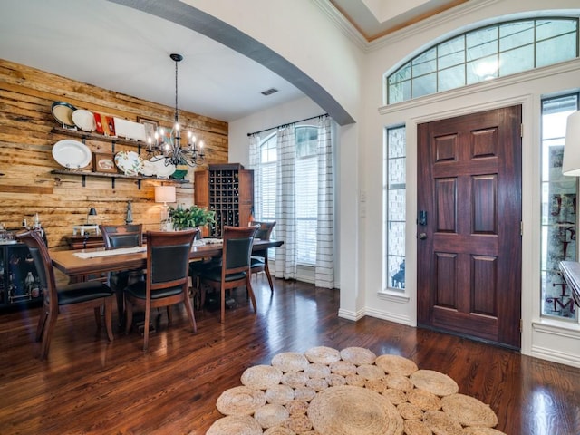 entrance foyer with dark wood-type flooring, wooden walls, and a healthy amount of sunlight