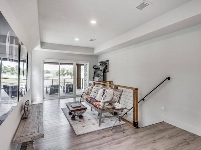 sitting room featuring hardwood / wood-style flooring and a raised ceiling