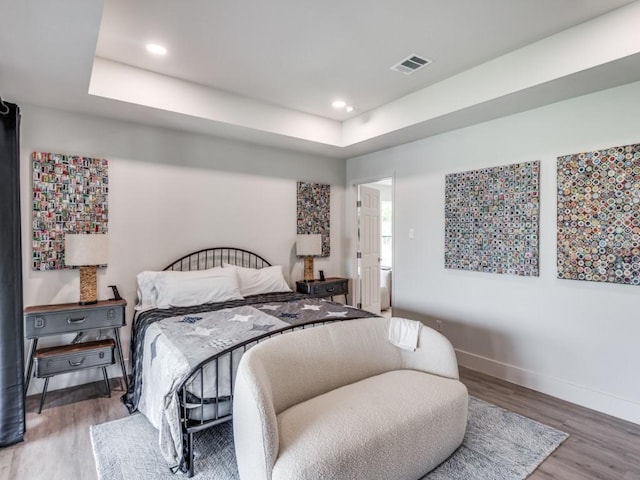 bedroom featuring hardwood / wood-style flooring and a raised ceiling