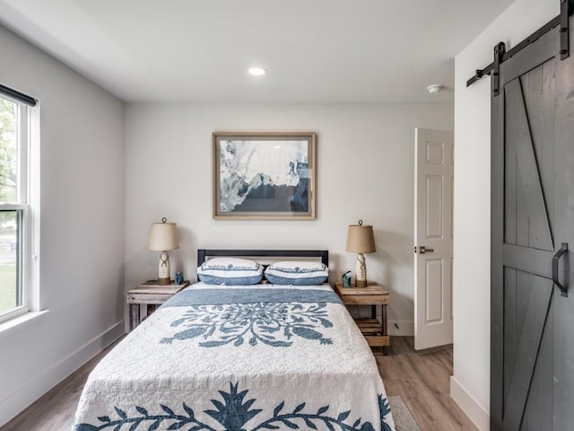 bedroom featuring wood-type flooring and a barn door