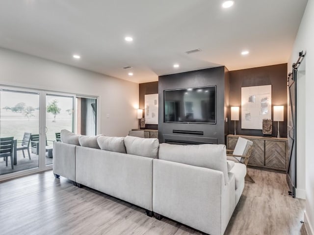 living room with a barn door and light hardwood / wood-style flooring