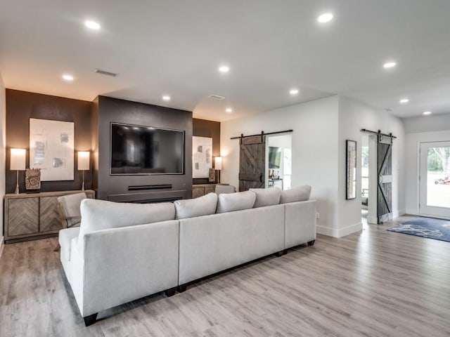 living room with a barn door and light wood-type flooring