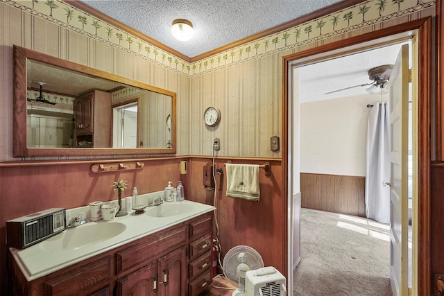 bathroom featuring vanity, wooden walls, ceiling fan, and a textured ceiling