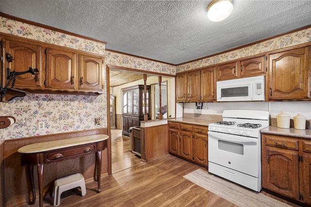 kitchen featuring white appliances, ornamental molding, a textured ceiling, and light wood-type flooring