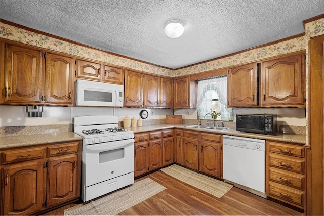 kitchen with white appliances, ornamental molding, light hardwood / wood-style floors, and sink