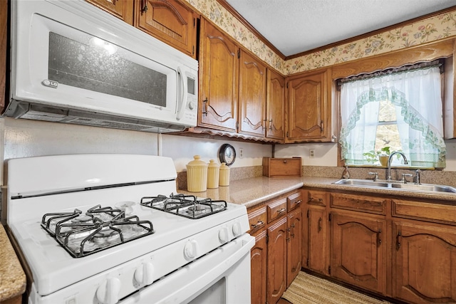 kitchen featuring white appliances, sink, and a textured ceiling