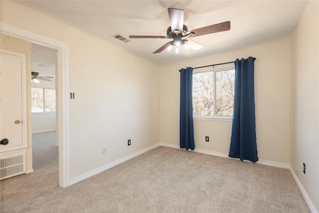 carpeted empty room featuring ceiling fan and a wealth of natural light