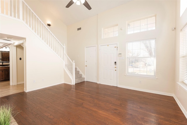 foyer entrance with ceiling fan, a towering ceiling, and dark hardwood / wood-style flooring