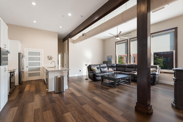 living room featuring sink, ceiling fan, decorative columns, dark hardwood / wood-style flooring, and beamed ceiling