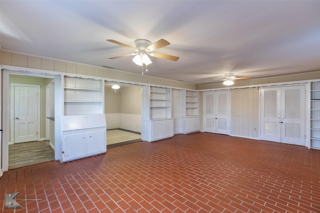 interior space featuring ceiling fan and wood walls