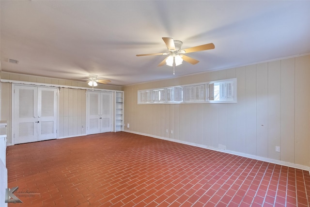 interior space featuring multiple closets, ceiling fan, and wood walls