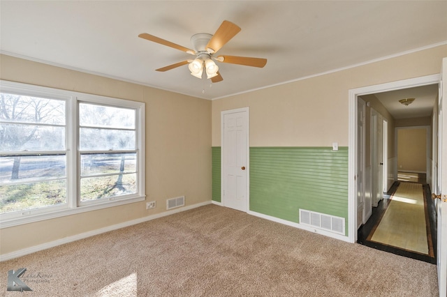 spare room featuring crown molding, carpet, and ceiling fan