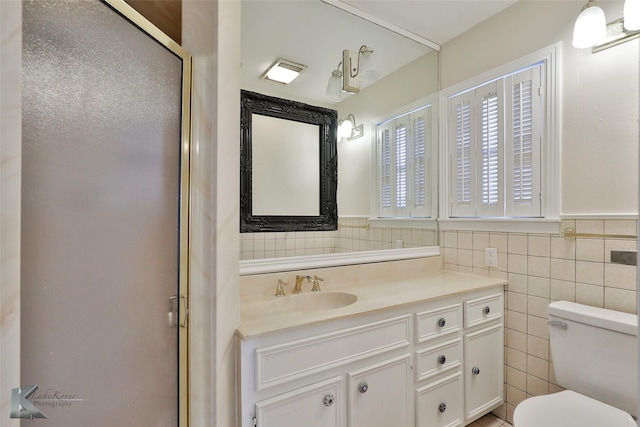 bathroom featuring vanity, toilet, an enclosed shower, and tile walls