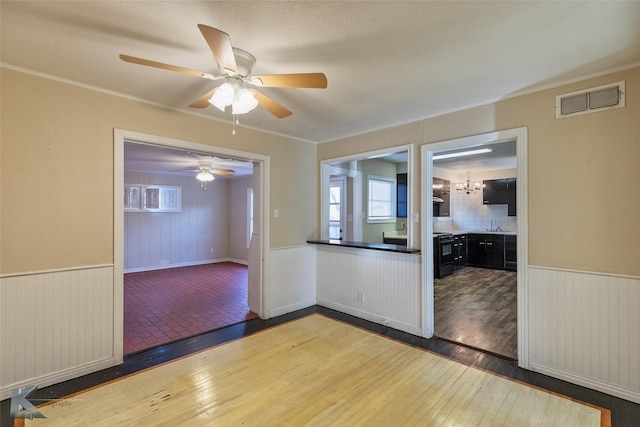 unfurnished room featuring sink, ceiling fan with notable chandelier, and dark wood-type flooring