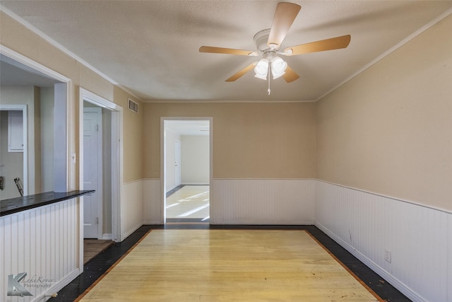 empty room with ceiling fan, ornamental molding, hardwood / wood-style floors, and a textured ceiling