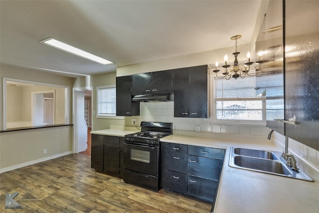 kitchen with black gas range oven, sink, hanging light fixtures, hardwood / wood-style floors, and a wealth of natural light