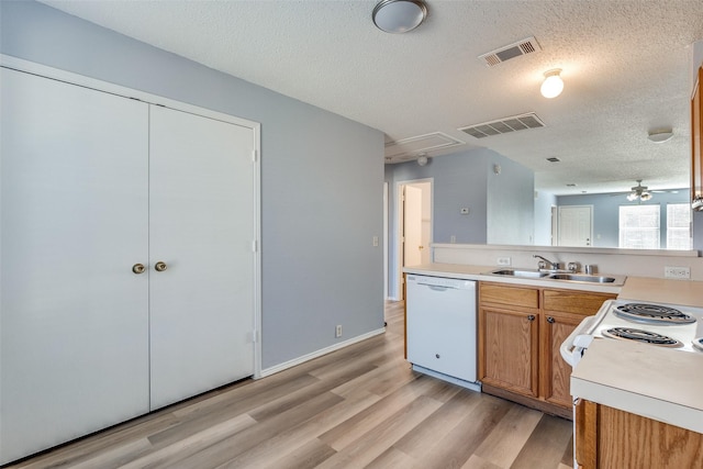kitchen with light wood-style flooring, a textured ceiling, visible vents, white appliances, and light countertops