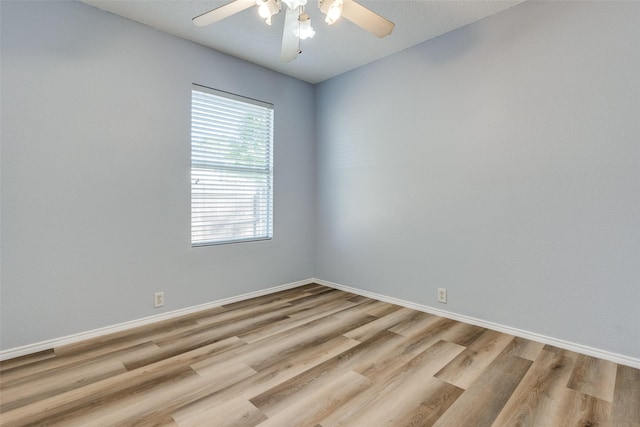 spare room with light wood-style flooring, a ceiling fan, and baseboards