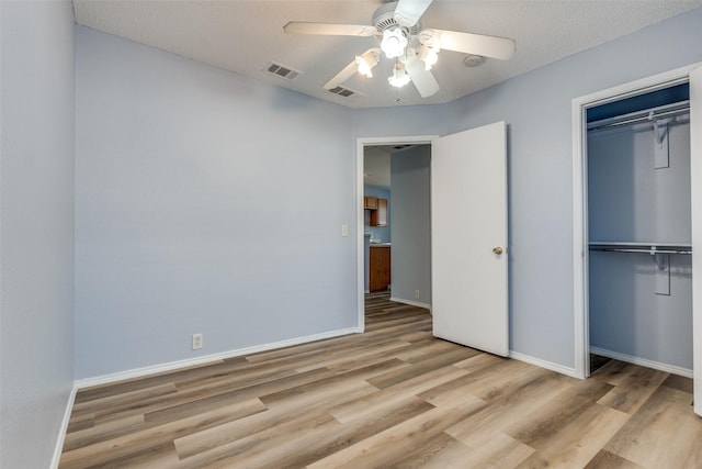 unfurnished bedroom with a closet, wood finished floors, visible vents, and baseboards