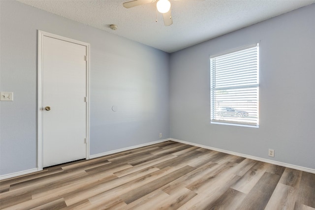 spare room with baseboards, a ceiling fan, wood finished floors, and a textured ceiling