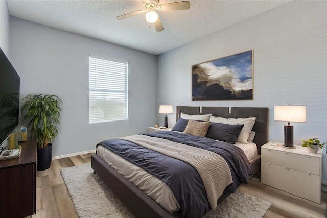 bedroom featuring a ceiling fan, a textured ceiling, and light wood-style floors